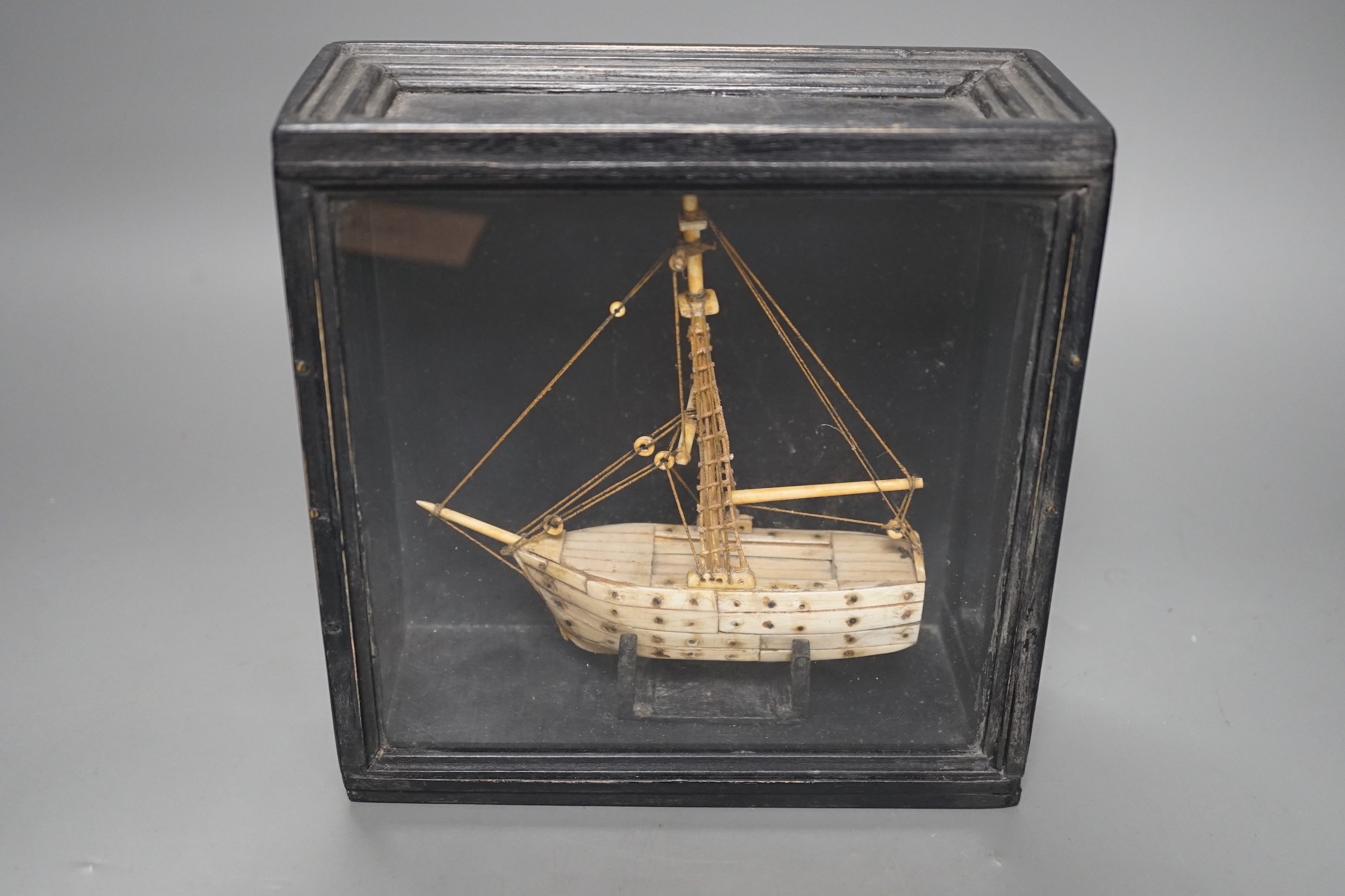 A cased bone Napoleonic style, carved prisoner-of-war ship, 18cms wide x 18.5cms high